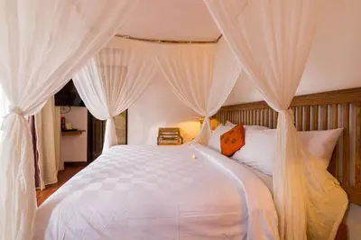 a bedroom with a white bed with drapes at New Pondok Sara Villas in Seminyak