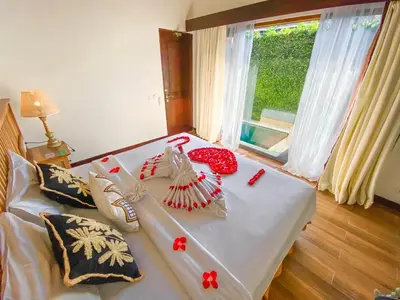 a bed with red and white pillows on it at New Pondok Sara Villas in Seminyak