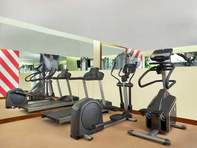 a gym with several exercise bikes and a mirror at Avani Seminyak Bali Resort in Seminyak