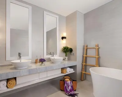 a bathroom with two sinks and a tub and two mirrors at Avani Seminyak Bali Resort in Seminyak