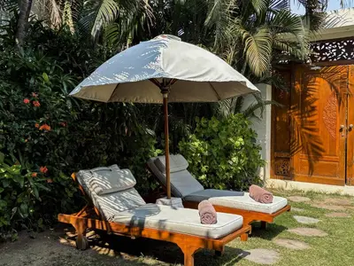 two loungers and an umbrella and chairs under it at Villa Chocolat Seminyak in Seminyak