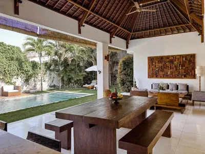 a living room with a wooden table and a pool at Villa Chocolat Seminyak in Seminyak