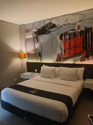a bedroom with a large bed with a painting on the wall at Loft Legian Hotel Bali in Legian