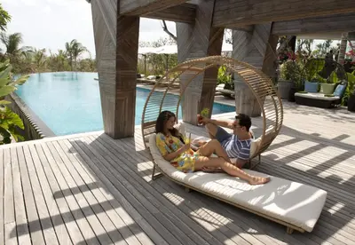 a man and a woman sitting on a swing by a pool at AYANA Resort Bali in Jimbaran