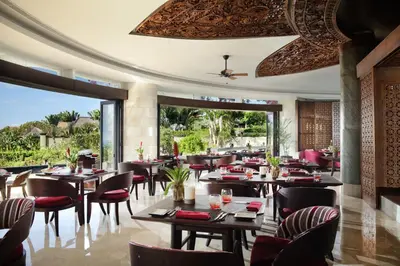a restaurant with tables and chairs and a large window at AYANA Resort Bali in Jimbaran
