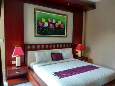 a bedroom with a bed with two lamps and a painting of flowers at D'Kubu Legian in Legian