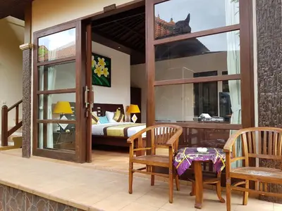 a room with a bed and a table and chairs at D'Kubu Legian in Legian