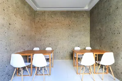 a meeting room with wooden tables and white chairs at Kak Garden Inn in Kuta