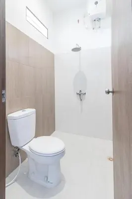 a bathroom with a white toilet in a room at Kak Garden Inn in Kuta