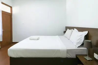 a bedroom with a large bed with white sheets and pillows at Kak Garden Inn in Kuta