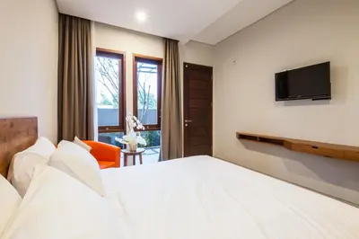 a hotel room with a bed and a television at Eclipse Kerobokan in Kerobokan