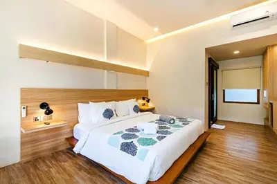 a bedroom with a large white bed and wooden floors at Kashantee Village in Seminyak