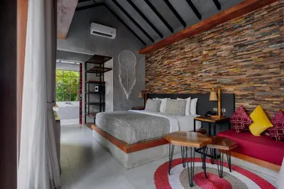 a bedroom with a bed and a brick wall at Vinna Villa Seminyak by The Wina Resorts in Kerobokan