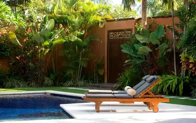 a pool with a chaise lounge next to a resort at The Kunja Villa-Hotel in Seminyak