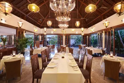 a restaurant with white tables and chairs and a chandelier at Gending Kedis Luxury Villas & Spa Estate in Jimbaran