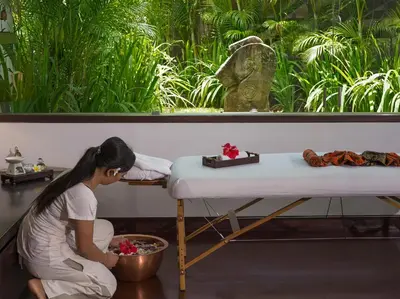 a woman sitting next to a table in a room at The Layar - Designer Villas and Spa in Seminyak