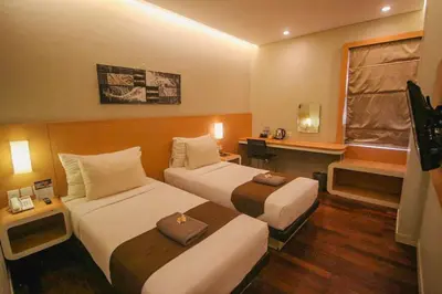 a hotel room with two beds and a window at Kuta Majesty Hotel in Legian