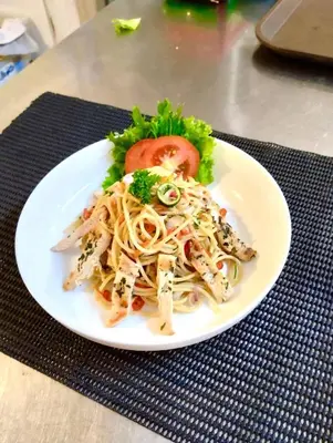 a plate of pasta with a tomato on a table at Kuta Majesty Hotel in Legian