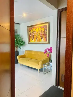 a yellow couch in a living room with a painting at Kuta Majesty Hotel in Legian