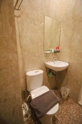 a bathroom with a sink and a toilet and a mirror at Kuta Majesty Hotel in Legian