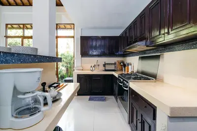 a kitchen with dark wooden cabinets and a sink at MAHAYANA VILLA - 7Min Beach Access - 10min to Canggu in Canggu