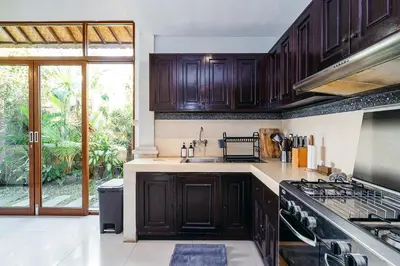 a kitchen with dark wood cabinets and a sink at MAHAYANA VILLA - 7Min Beach Access - 10min to Canggu in Canggu