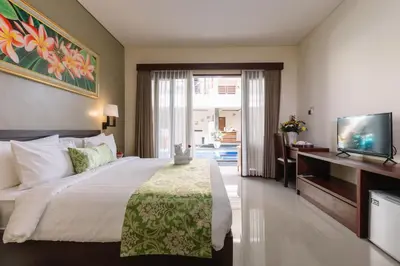 a hotel room with a bed and a television at Kubu Benoa Guest House in Nusa Dua