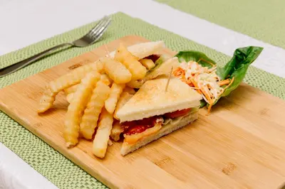 a sandwich and french fries on a cutting board at Kubu Benoa Guest House in Nusa Dua
