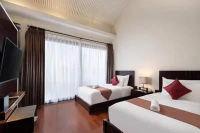 a hotel room with two beds and a flat screen tv at 18 Suite Villa Kuta in Kuta