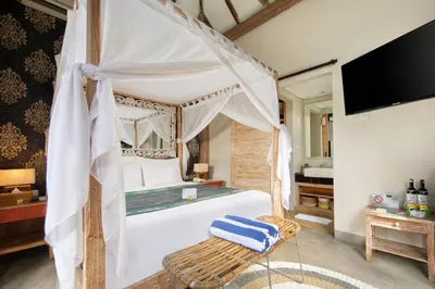 a bedroom with a canopy bed and a television at 18 Suite Villa Kuta in Kuta