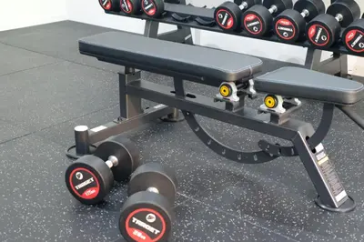 a bench with lots of dumbbells in a gym at Adi Dharma Hotel Kuta in Kuta