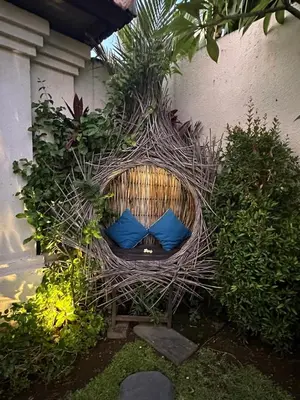 a wicker chair with blue pillows in a garden at Sarayu Villa in Seminyak