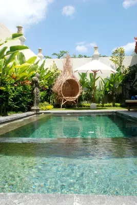 a swimming pool in front of a house at Sarayu Villa in Seminyak