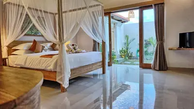 a bedroom with a canopy bed with curtains at Sarayu Villa in Seminyak