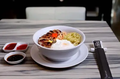a bowl of food on a table with noodles at Hotel Neo - Kuta, Jelantik in Legian