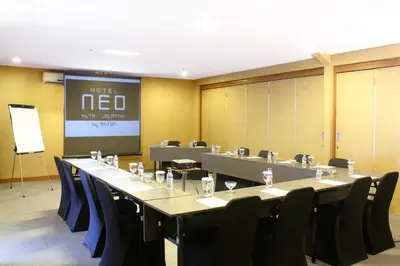 a conference room with a long table and chairs at Hotel Neo - Kuta, Jelantik in Legian