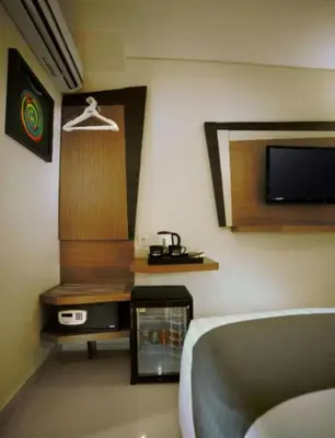 a room with a bed and a tv on a wall at Hotel Neo - Kuta, Jelantik in Legian