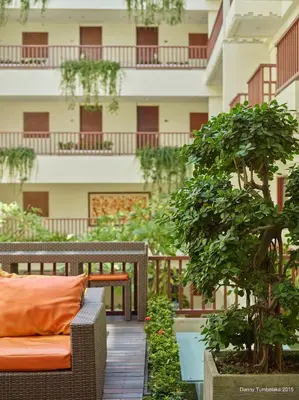 a balcony with a couch and a tree in front of a building at Sense Sunset Hotel Seminyak in Seminyak