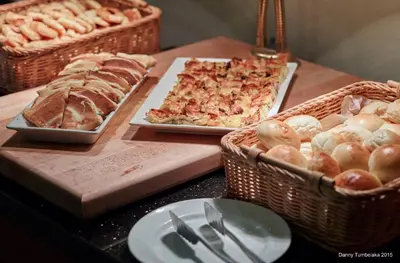a table topped with plates of food and baskets of bread at Sense Sunset Hotel Seminyak in Seminyak