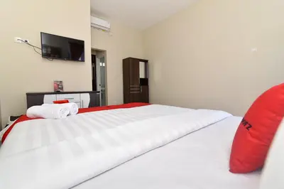 a bedroom with a large white bed with a red pillow at RedDoorz Plus near Jalan Imam Bonjol Denpasar in Seminyak