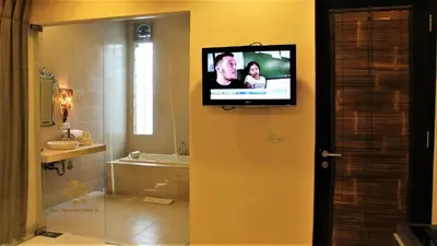 a bathroom with a flat screen tv on a wall at The Nibbana Villas in Seminyak