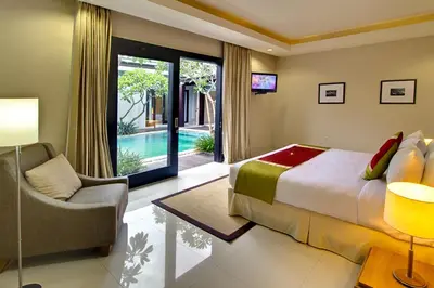 a bedroom with a bed and a chair and a pool at The Nibbana Villas in Seminyak