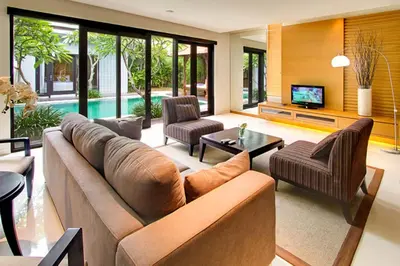 a living room with a couch and chairs and a tv at The Nibbana Villas in Seminyak