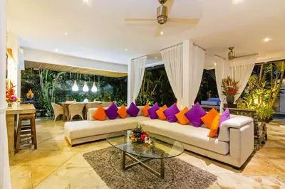 a living room with a white couch with colorful pillows at Villa Eindra Seminyak in Seminyak