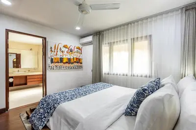 a bedroom with a large white bed and a bathroom at Elina Villas Seminyak in Seminyak