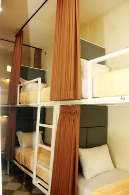 two bunk beds with orange curtains in a room at ALA Hostel in Seminyak