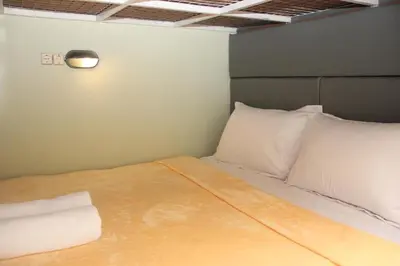 a bed with white pillows and a light on the wall at ALA Hostel in Seminyak