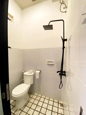 a white bathroom with a toilet and a shower at ALA Hostel in Seminyak