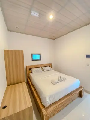 a bedroom with a bed with a wooden frame at ALA Hostel in Seminyak