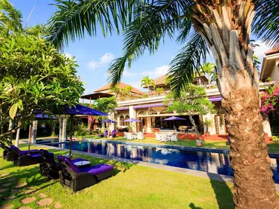 a resort pool with chairs and a palm tree at Sayang d'Amour in Seminyak
